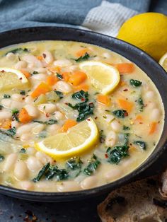 a bowl of white bean soup with lemons and spinach on the side next to bread