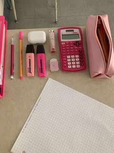 a pink calculator, pen, pencils, and other items on a table