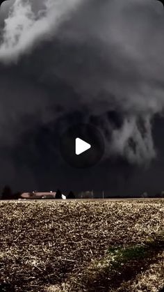 a black and white photo of a storm moving through the sky over a farm field