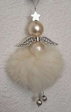 an ornament hanging on the wall with pearls and feathers