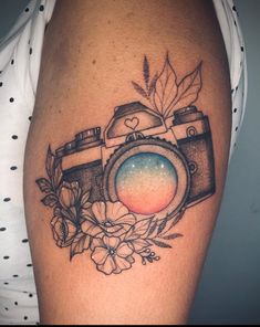 a tattoo with a camera and flowers on it