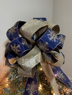 a blue and gold christmas tree bow with snowflakes on the top is shown