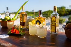 there are many bottles and glasses on the table with drinks in them, including lemonade