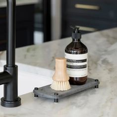 a soap dispenser sitting on top of a counter next to a brush