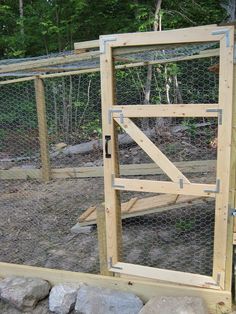 an open gate in the middle of a yard with rocks and trees behind it,