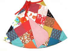 a colorful patchwork skirt with a red bow on the front and bottom, sitting on a white surface