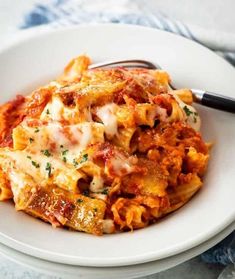 a white plate topped with pasta covered in sauce and cheese