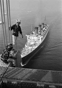 a man standing on the side of a bridge next to a large ship in the water