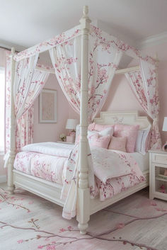 a white four poster bed with pink flowers on the covers and pillows in a bedroom