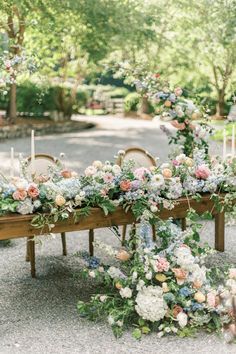 a long table with flowers and candles on it is set up for an outdoor wedding