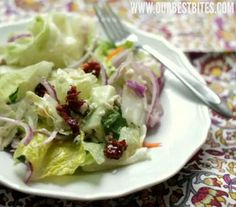 a white plate topped with lettuce and cranberry salad next to a fork