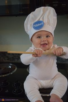 a baby wearing a chef's hat and holding a wooden spoon