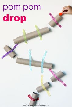 a hand is holding some paper rolls and stringing them together to make a diy pom pom drop