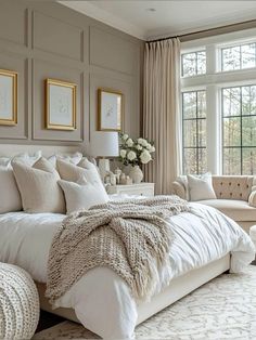 a large white bed sitting in a bedroom next to a window filled with lots of windows