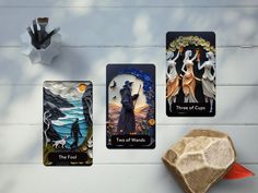 three different cards with the four of wands on them next to a wooden object