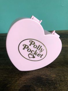 a white heart shaped object with the words polly pocket on it's side