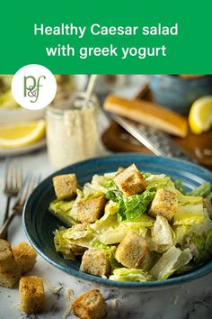 a blue bowl filled with salad and croutons on top of a white table