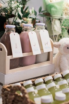 a teddy bear sitting in front of bottles of juice on a table with other items