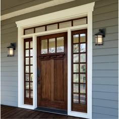 the front door of a house with two lights on each side and an open window