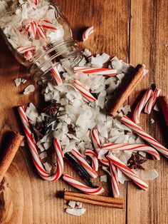 some candy canes and cinnamon sticks are on the table next to an empty jar