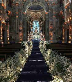 the interior of a church decorated with flowers and greenery on either side of the aisle