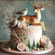 a cake decorated with deer and birds on top of a wooden table next to a wall