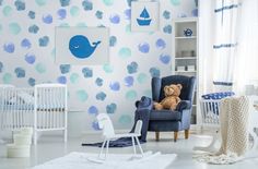 a baby's room with blue and white wallpaper, crib, rocking chair and teddy bear