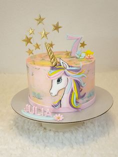 a pink unicorn cake with gold stars on top and the number one on it's side