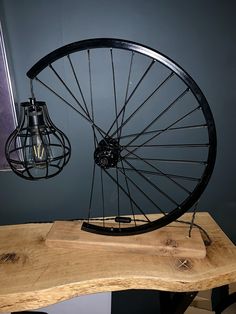 an old bicycle wheel is sitting on top of a wooden table next to a light bulb