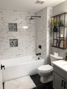 a white toilet sitting next to a bath tub in a bathroom on top of a black and white floor