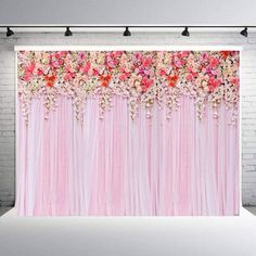 a pink backdrop with flowers on it in front of a white brick wall and black lights