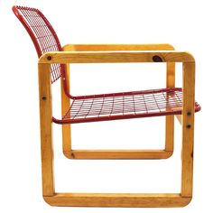 a wooden chair with a red wire shelf on it's back end and legs