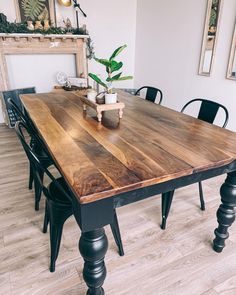 a wooden table with black chairs and a potted plant