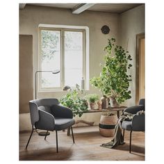 a living room filled with furniture and potted plants on top of a wooden floor