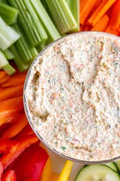 a bowl of vegetable cream cheese surrounded by celery and carrots