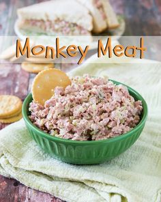 a green bowl filled with meat next to crackers