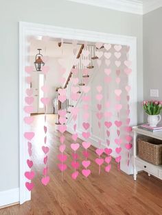 pink hearts hanging from the ceiling in front of a white wall with stairs and railings