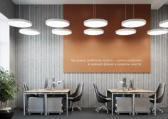 an office with two desks and four chairs in front of a large poster on the wall