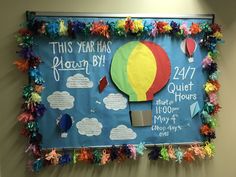 a bulletin board is decorated with colorful paper flowers and hot air balloons in the sky