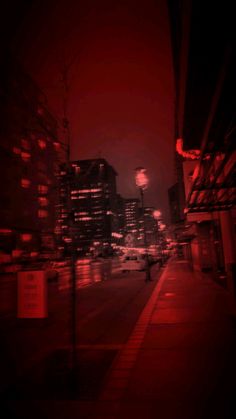 a city street at night with red lights and tall buildings in the backround