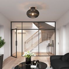 a living room with two black couches and a coffee table in front of a staircase