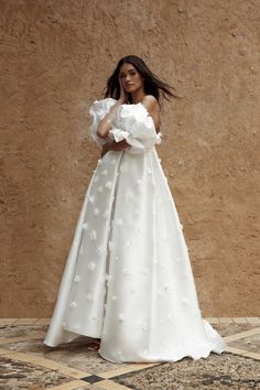 a woman in a white wedding dress standing against a wall