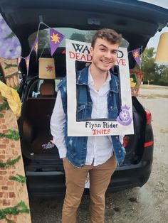 a man standing in front of a car holding a sign