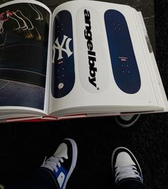 an open book with new york yankees stickers on the pages and someone's feet standing next to it