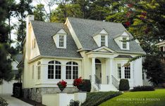 a white house with two story windows and flowers in the window boxes on the front