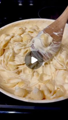 a pan filled with pasta being stirred by a spatula on top of the stove