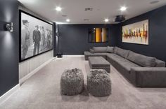 a modern home theater with grey couches and foot stools