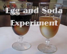 an egg and soda experiment is shown in two wine glasses on a white tablecloth