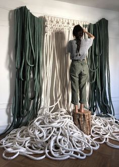 a woman standing on top of a pile of white ropes in front of a wall