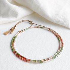 This delicate double wrap silk bracelet with a golden orange, succulent green and apricot beige glass beads has a sliding clasp to adjust to your size. As part of the California Dreaming collection the Joshua Tree bracelet is inspired by the Joshua Tree National park which is said to have a strong spiritual energy. On a natural beige silk cord with high quality tiny Japanese glass beads and 14k gold filled sliding clasp and beads. Fits an average wrist size of up to 7 inches and tightens to 6.25in. Extends to maximum of 8.5in to fit over the widest part of the hand. If you have a smaller or larger wrist and hands and would like a custom size please contact me. Displayed in one of our pretty gift boxes, so fantastic as a present for a friend or to yourself! Shipping Uk: 2-3 days - Royal Mai Green Resizable Friendship Bracelets With Round Beads, Adjustable Beige Beaded Bracelets With Tiny Beads, Adjustable Beige Beaded Bracelet With Tiny Beads, Adjustable Tiny Beads Wrap Bracelet Gift, Green Beaded Bracelets With Adjustable Length, Green Bracelets With Adjustable Round Beads, Green Bracelets With Adjustable Length And Round Beads, Orange Bohemian Bracelet With Adjustable Cord, Adjustable Beige Beaded Bracelets With Colorful Beads